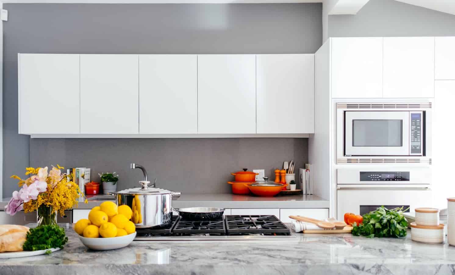 A thoroughly cleaned kitchen with white cabinets and a stainless steel cooktop