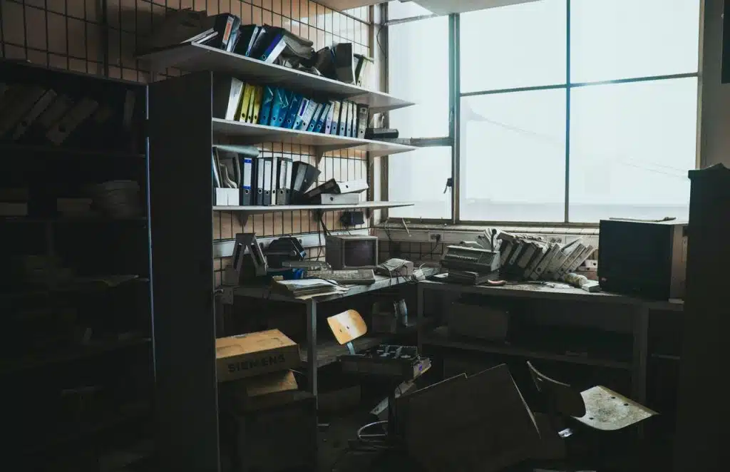 An extremely cluttered office space with old computers on tables