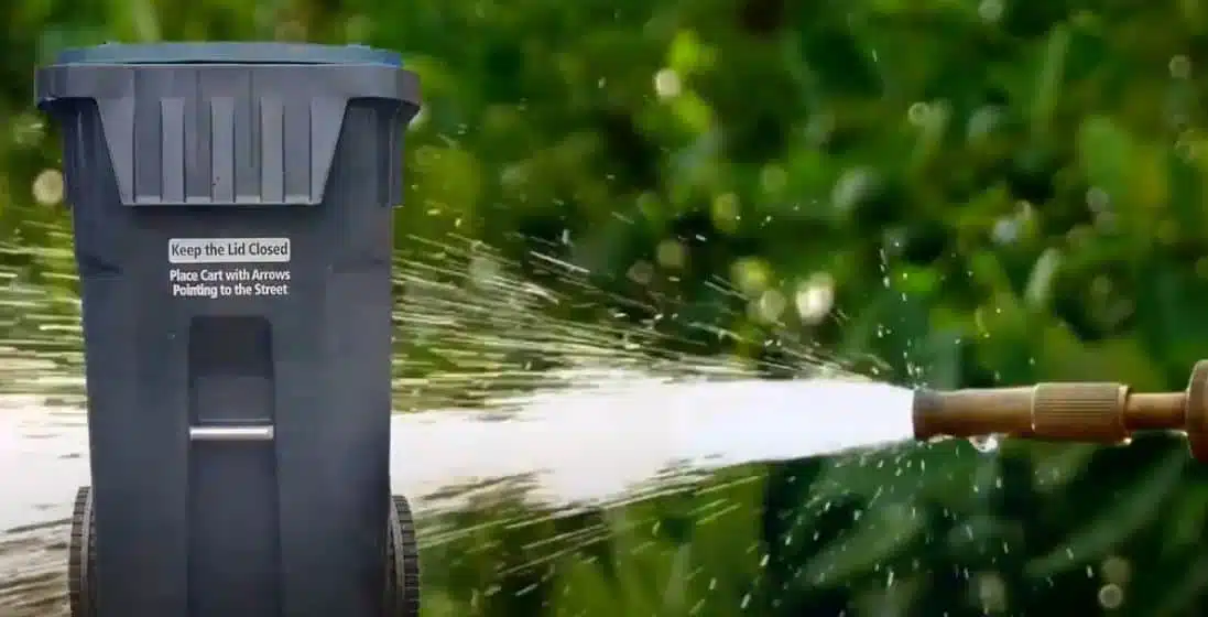 black wheelie bin being pressure washed