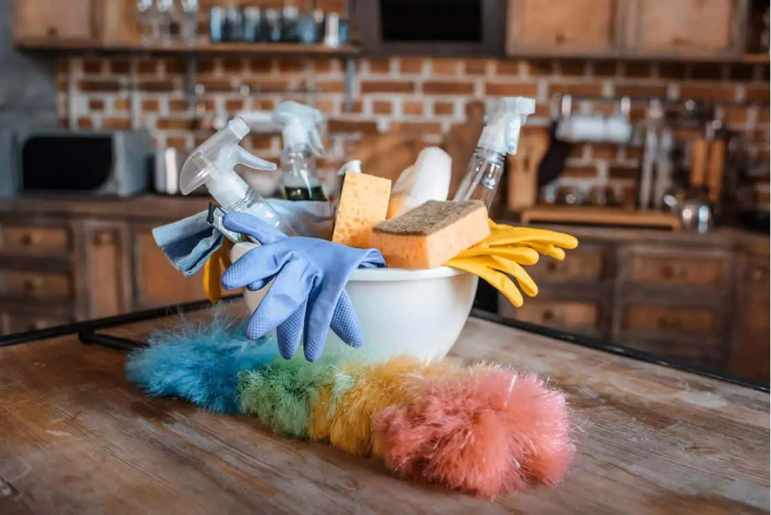 cleaning equipment, feather duster and gloves on a large wooden table