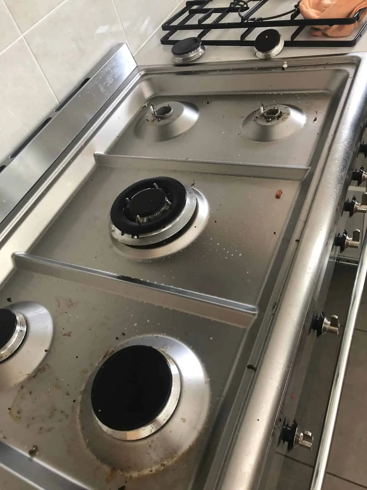 cleaning stainless steel stove top grates and burners on a large cooktop