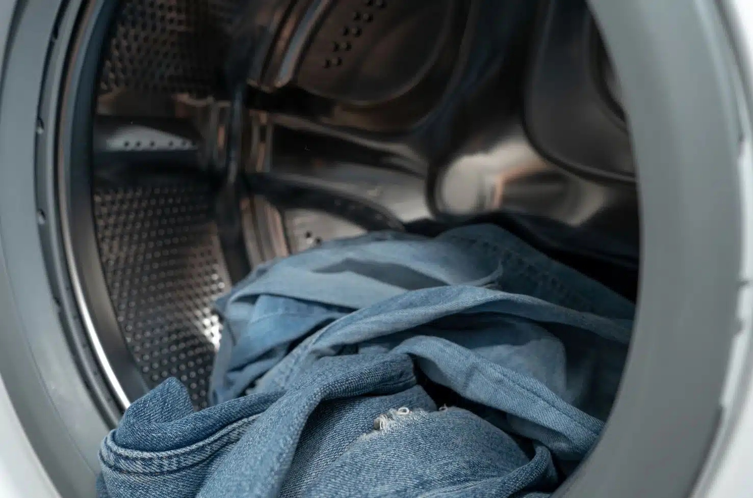 dirty crumbled blue jeans in a front loader washing machine
