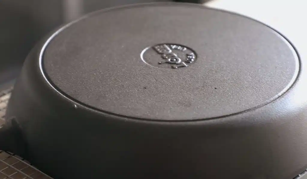 Cast iron skillet sitting top down on a bench after having its rust removed
