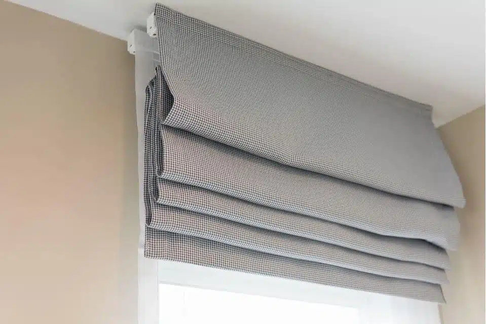 grey roman blinds opened on a window