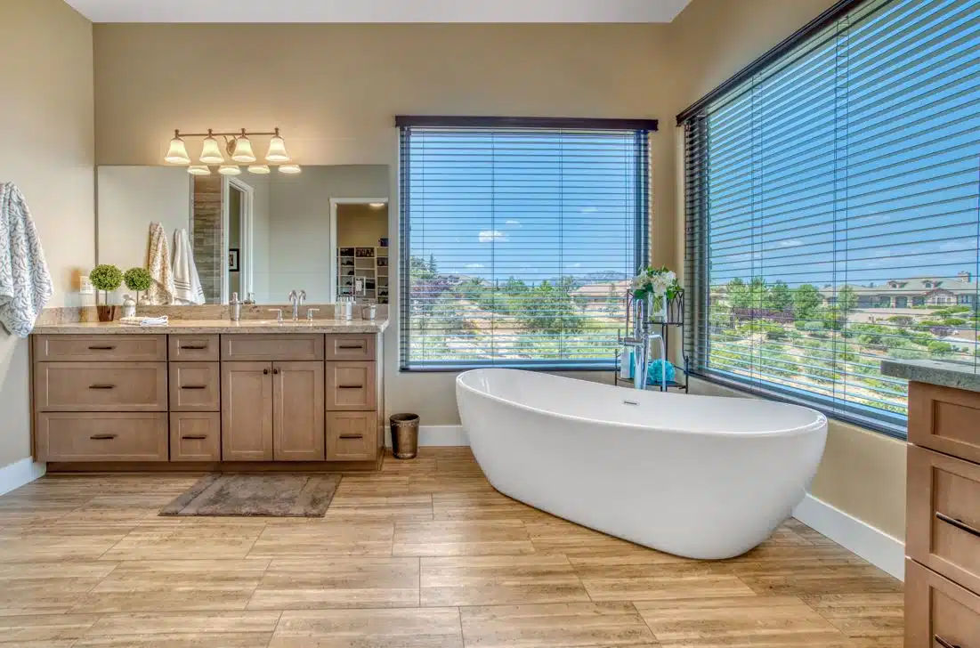 large mahogany bathroom with a large white porcelain bathtub in the background