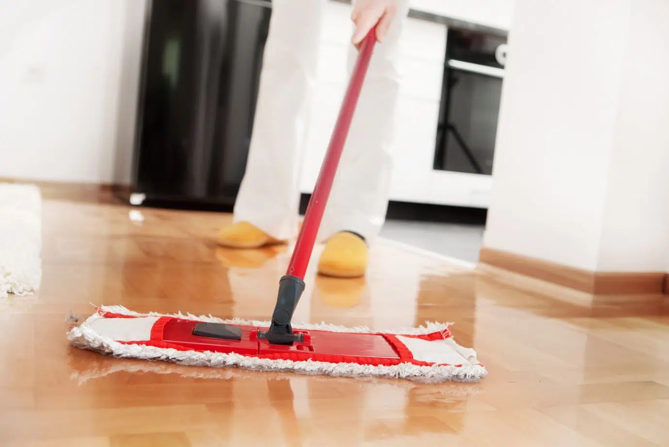 man using red mop to clean hardwood floor