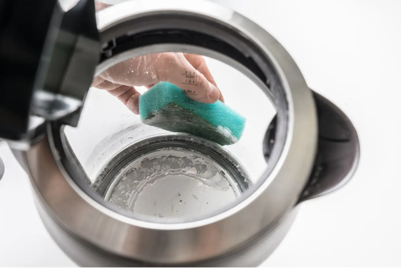 person cleaning the outside of a see-through kettle with a blue sponge