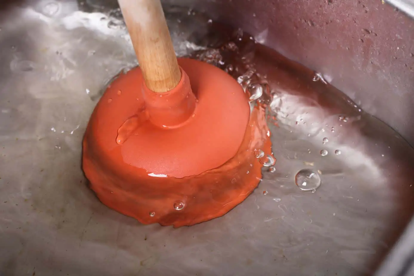 red plunger being used to unplug a drain