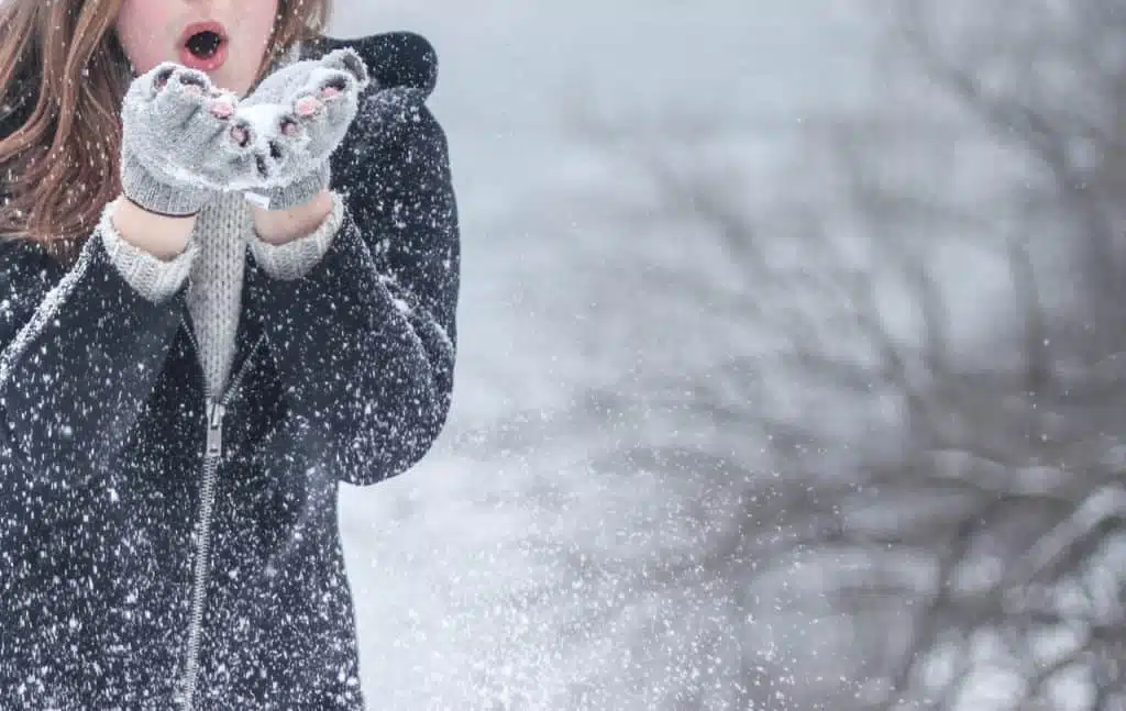 A girl blowing snow out of her hands