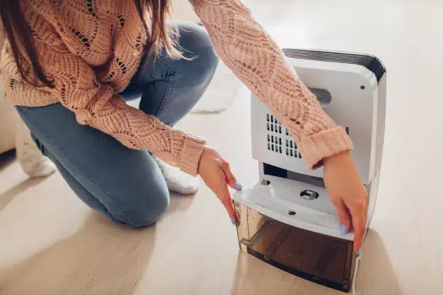 Woman changing water container dehumidifier