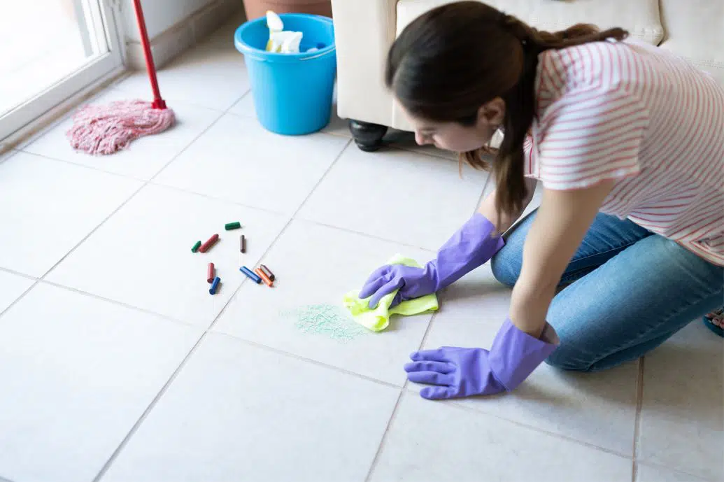 woman in white and red striped shirt cleaning crayon off white porcelain tiles