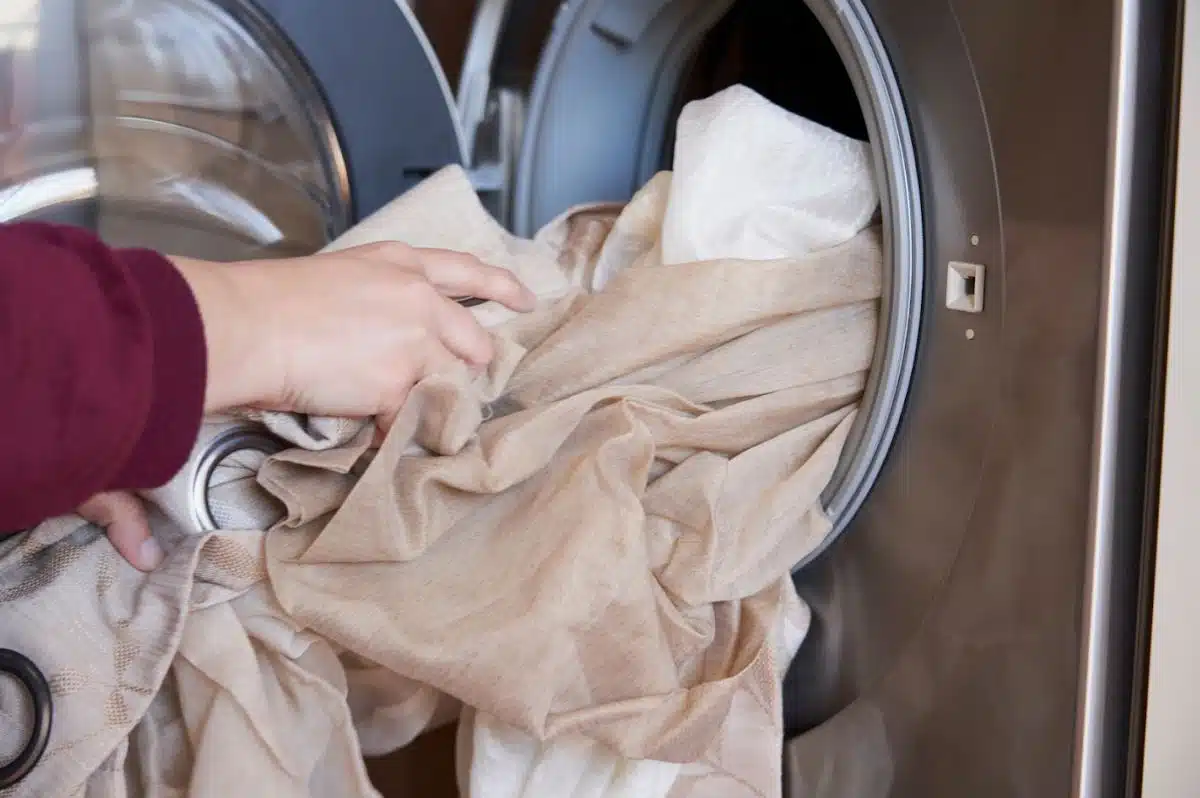woman packing brown curtain into a front load washing machine