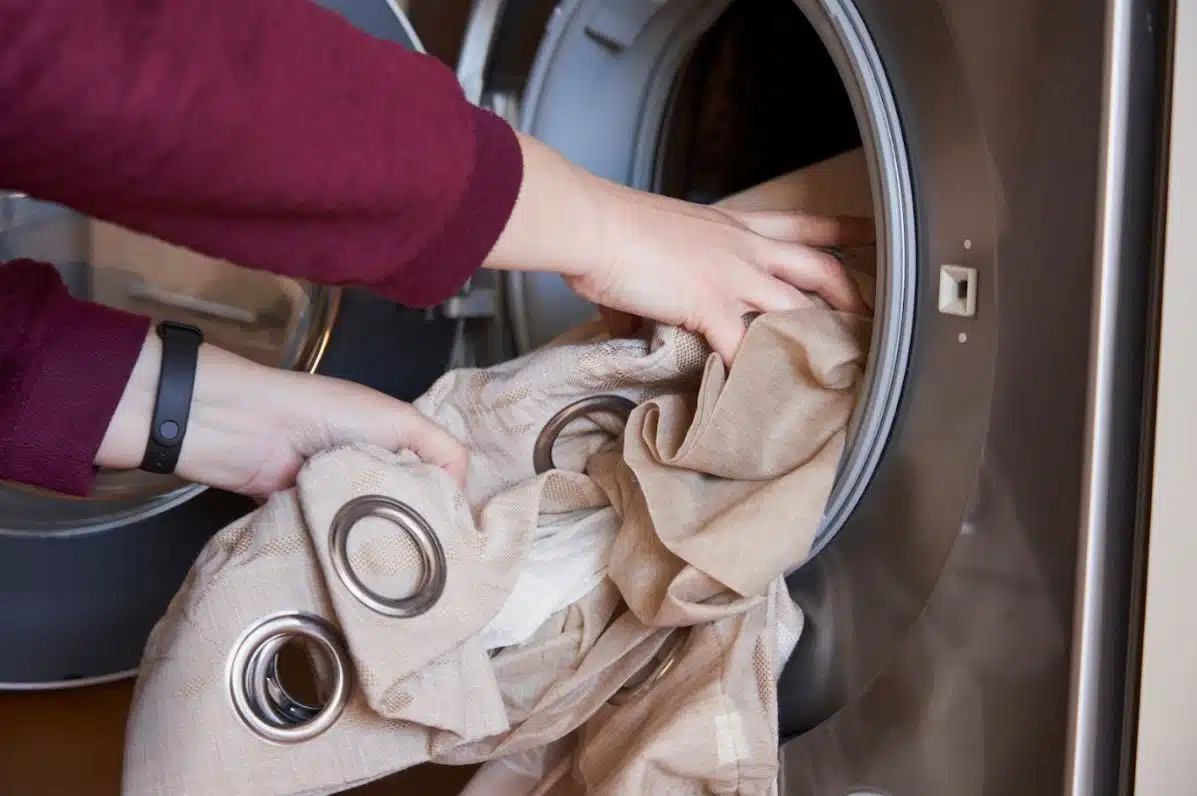 woman putting brown curtains in a front load washing machine