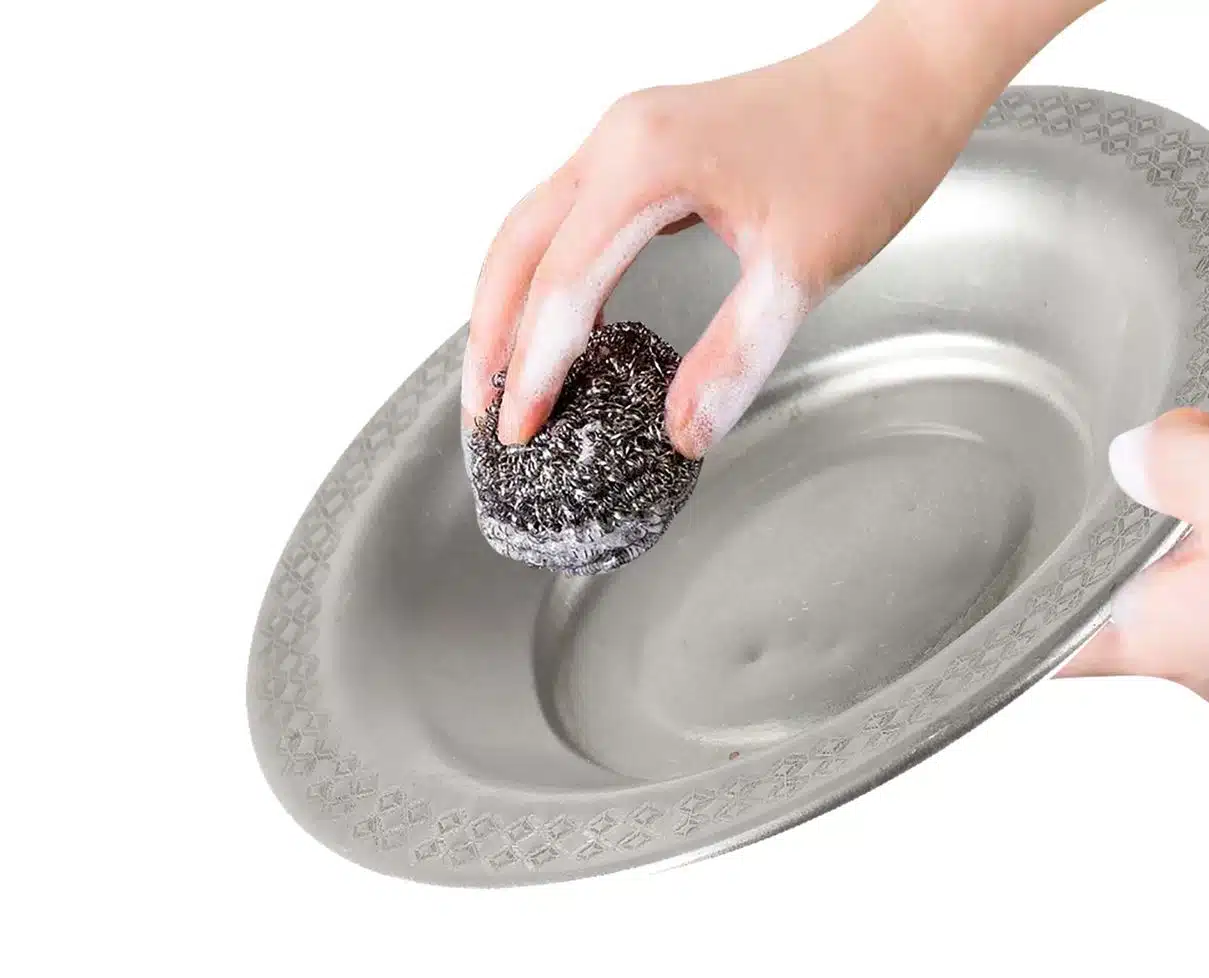 woman using steel wool to brush pewter plate