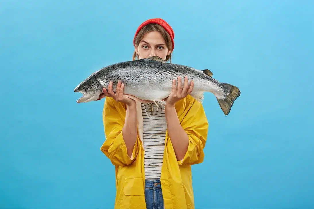woman wearing yellow jacket holding large fish